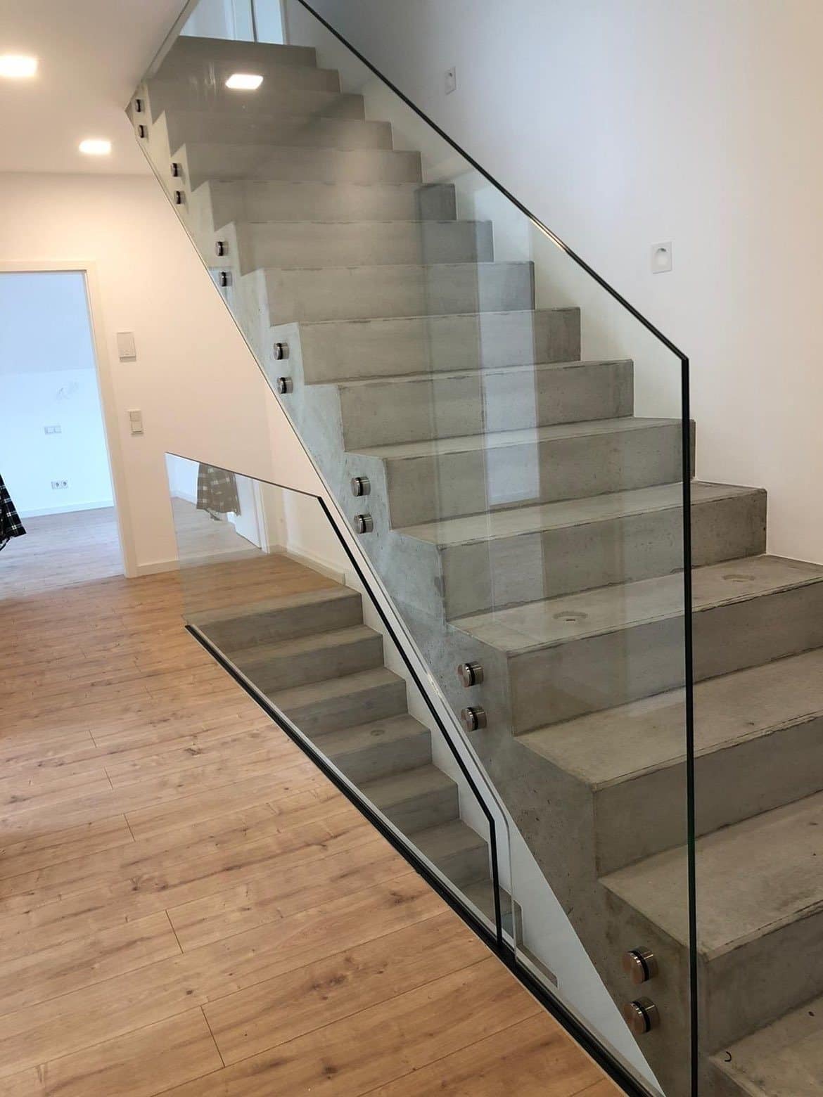 Rechte trap met glazen borstwering zonder stijlen, zijdelings bevestigd met stalen klemmen, in een nieuwbouwwoning